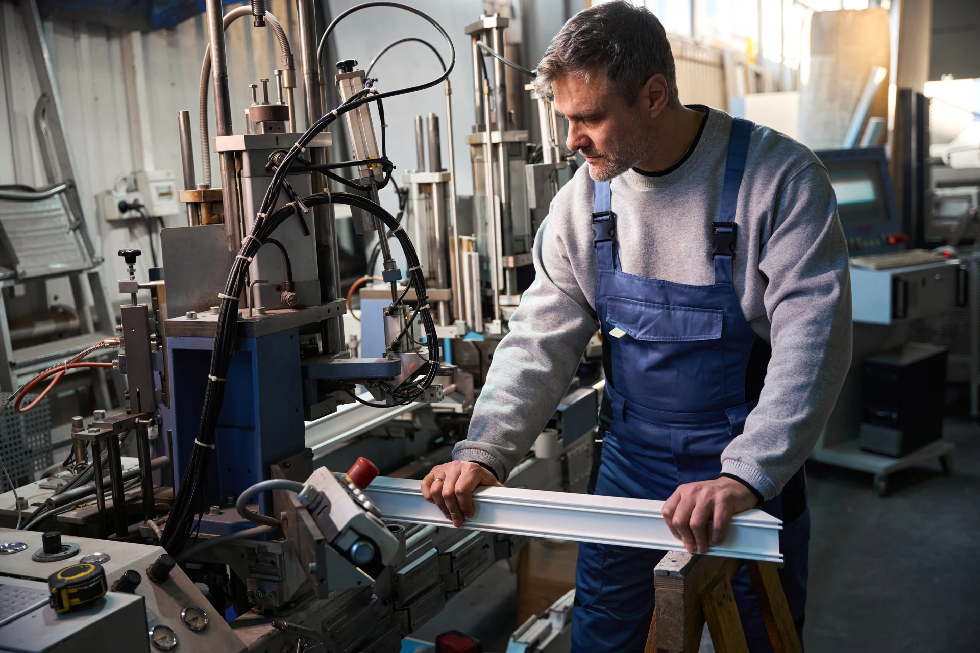 Technician operating machinery to fabricate an aluminium profile
